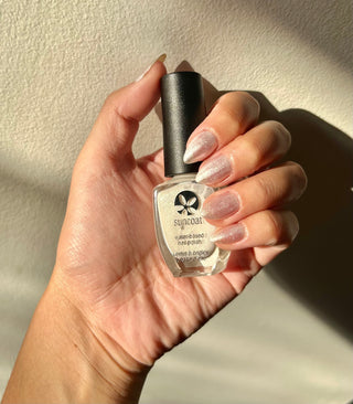 Hand holding a bottle of Glory nail polish against a neutral background